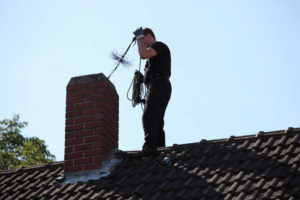 sweep on roof cleaning chimney