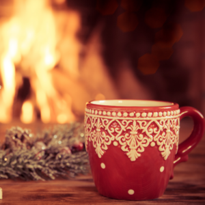 a red and white mug in front of a lit fireplace