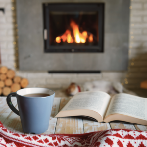 a blue mug and open book in front of a fireplace