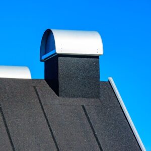 a black roof with a black prefab chimney covered by a curved metal (gray) chimney cap
